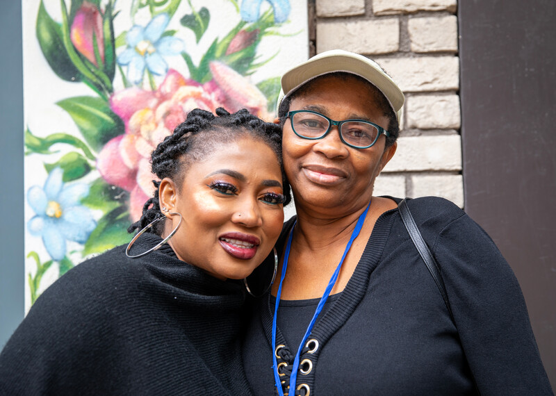 Esther and her daughter, Blessing embrace in front of a colourful mural.